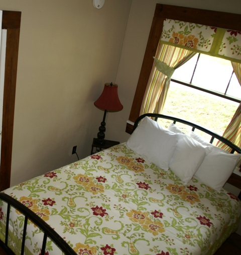 KONICA MINOLTA DIGITAL CAMERA bed with pillows and floral blankets with curtains