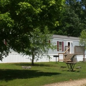 A park bench in the grass near a house.