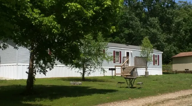 A park bench in the grass near a house.