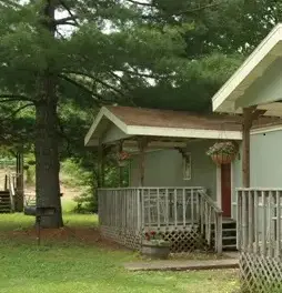 A house with a porch and fence in the yard.