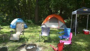 A group of chairs and tents in the grass.