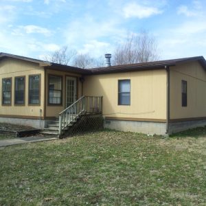A yellow house with stairs leading to the front.