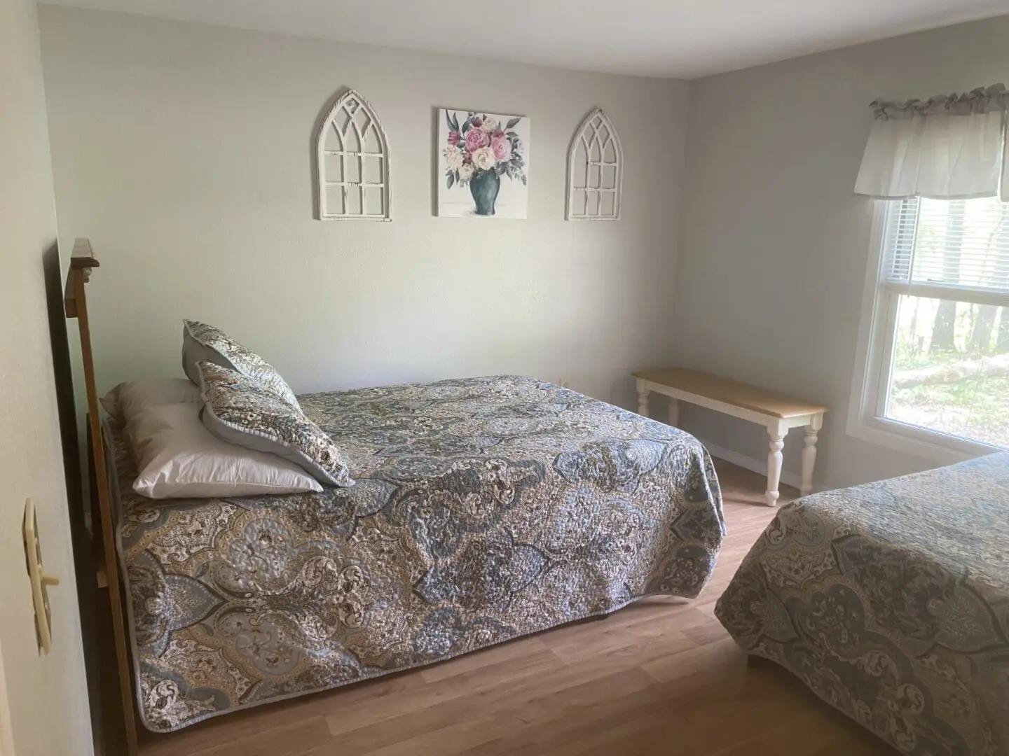 A bedroom with two beds and a bench in the corner.