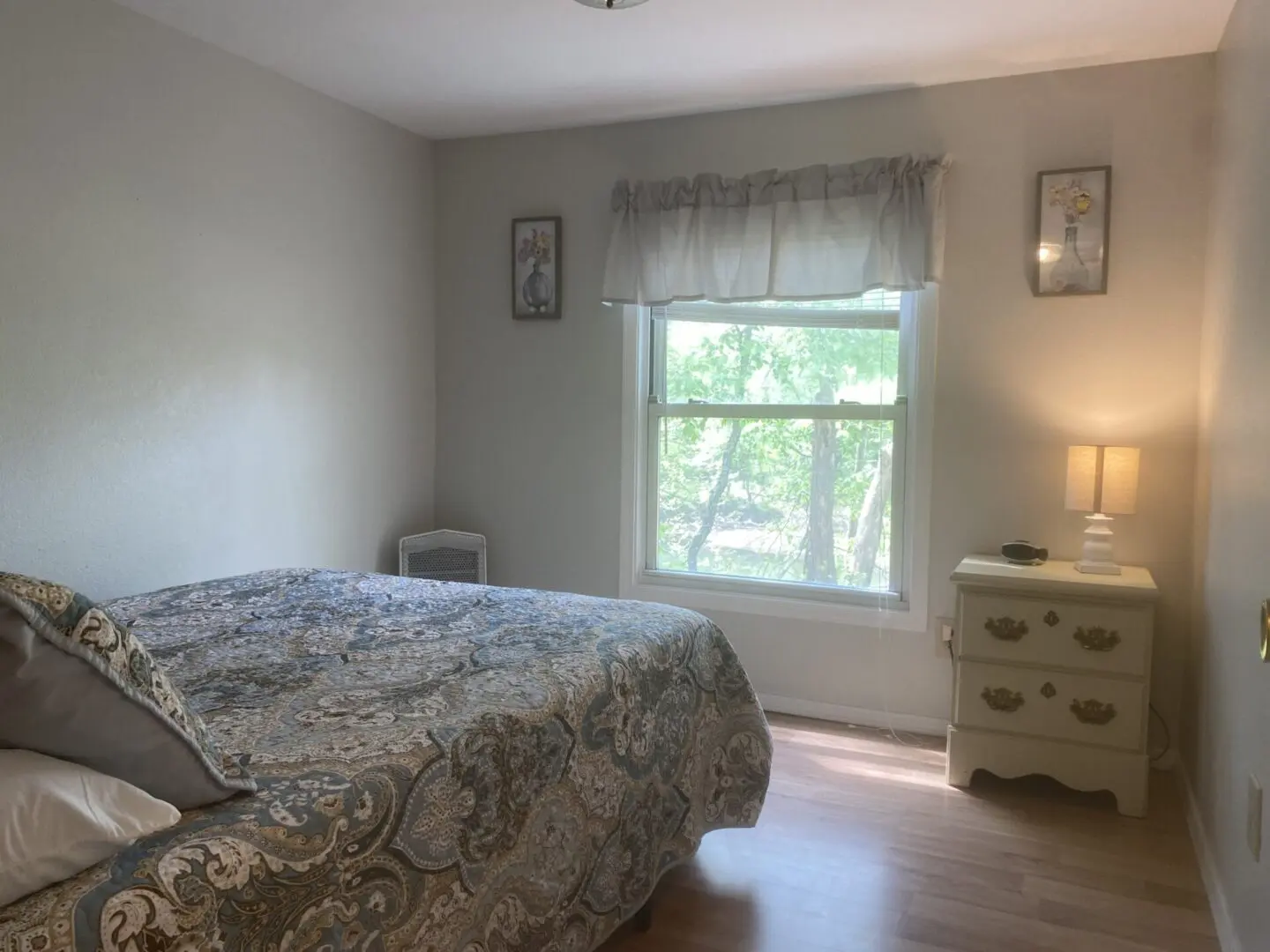 A bedroom with a bed, dresser and window.