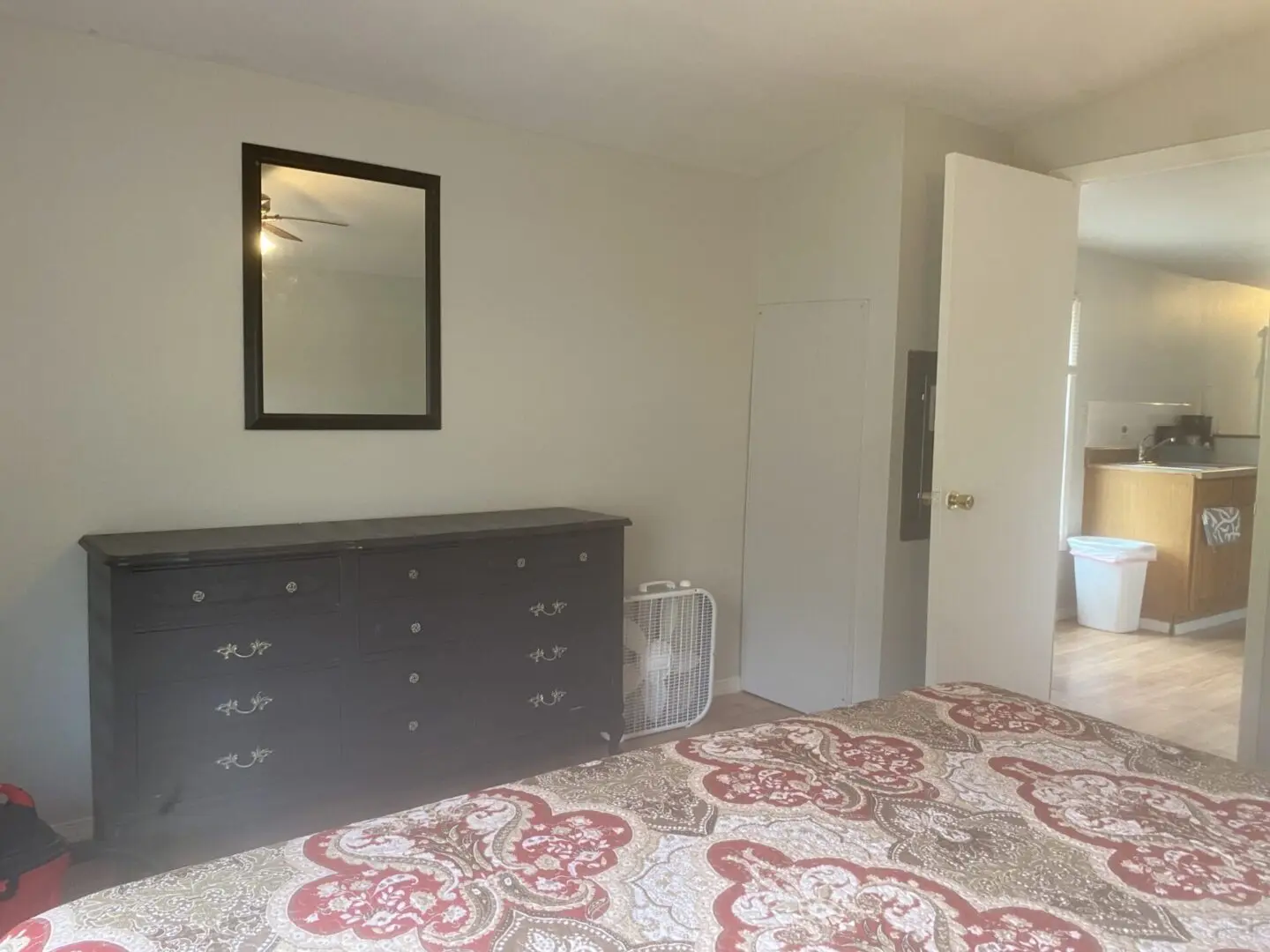 A bedroom with a dresser and mirror in it