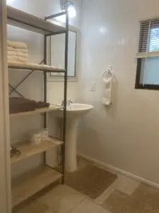 A bathroom with shelves and towels on the floor.