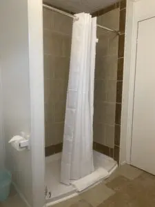 A shower with a curtain in the corner of a bathroom.