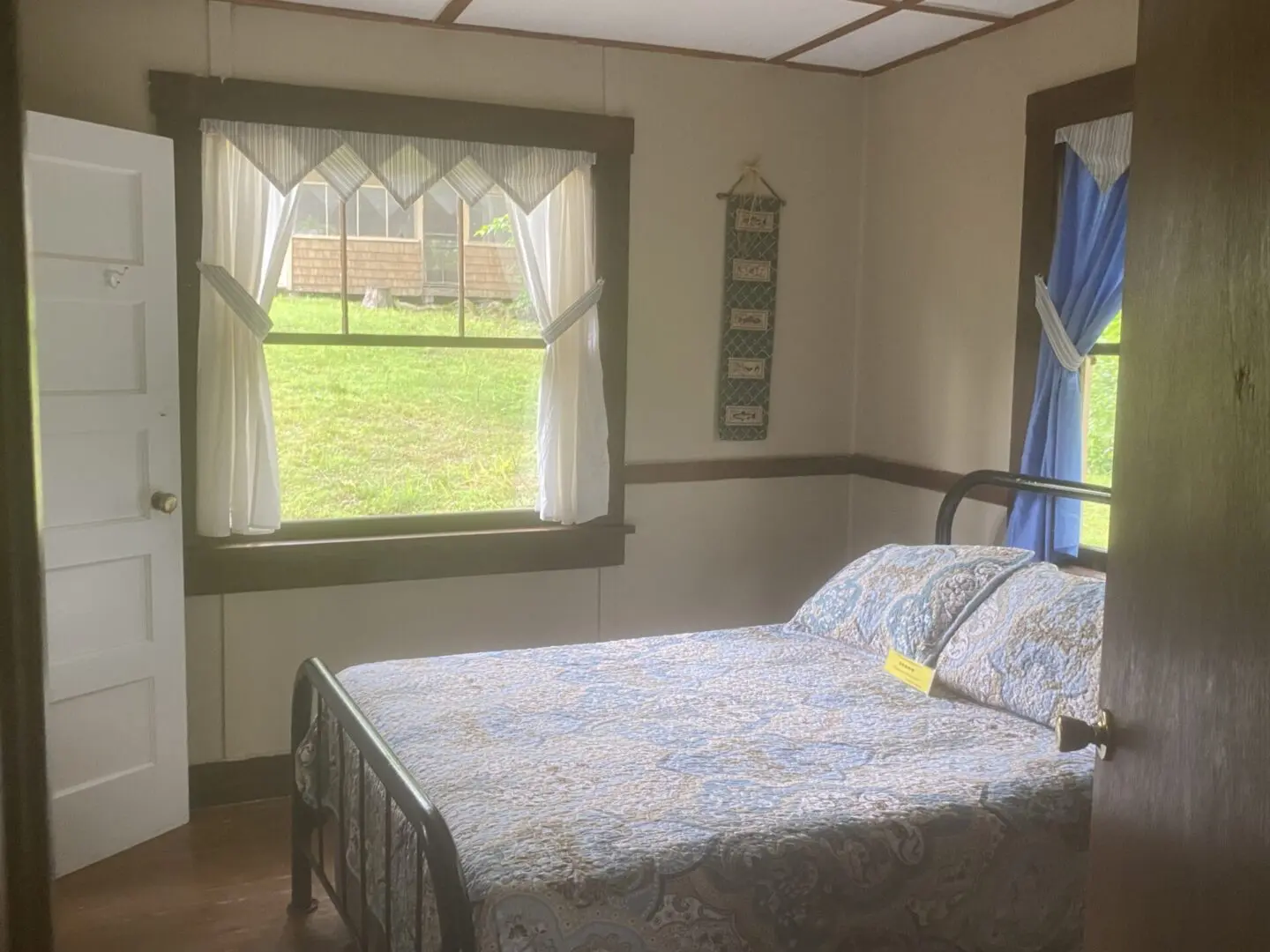 A bedroom with a bed and two windows.
