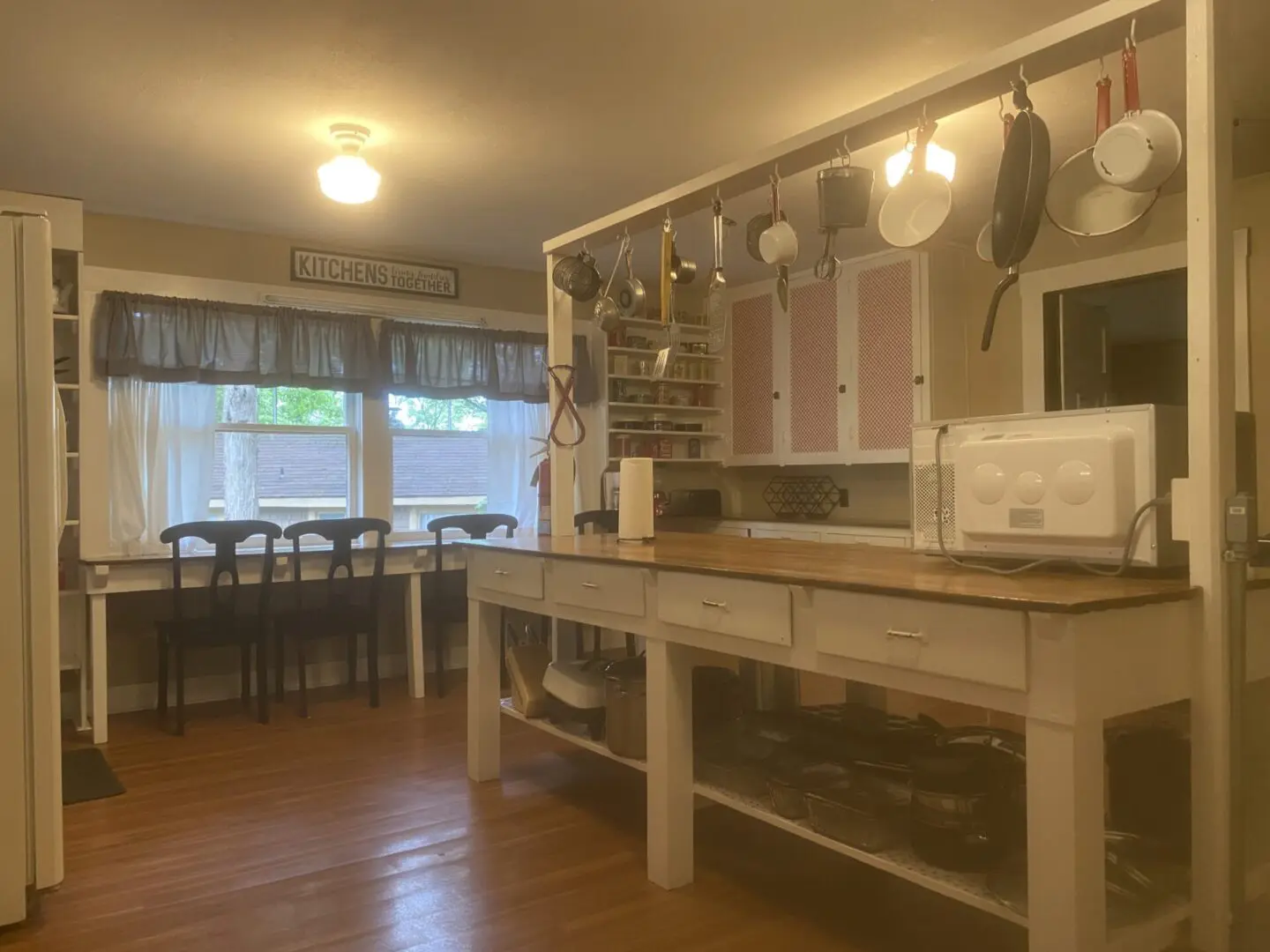 A kitchen with wooden floors and white cabinets.