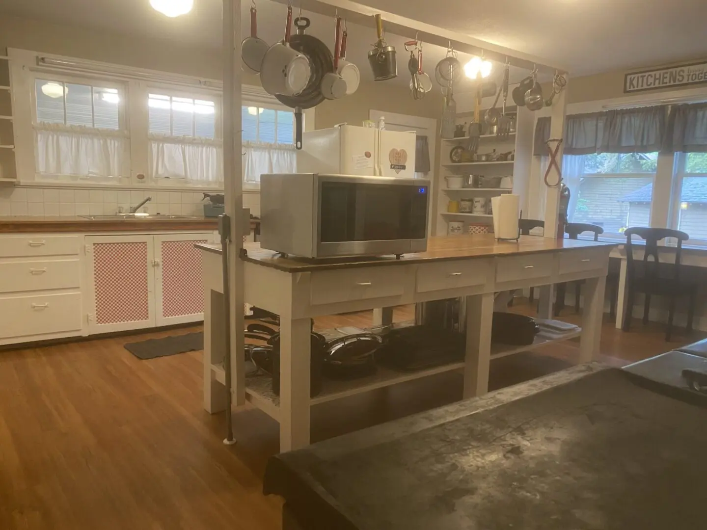 A kitchen with many pots and pans hanging from the ceiling.