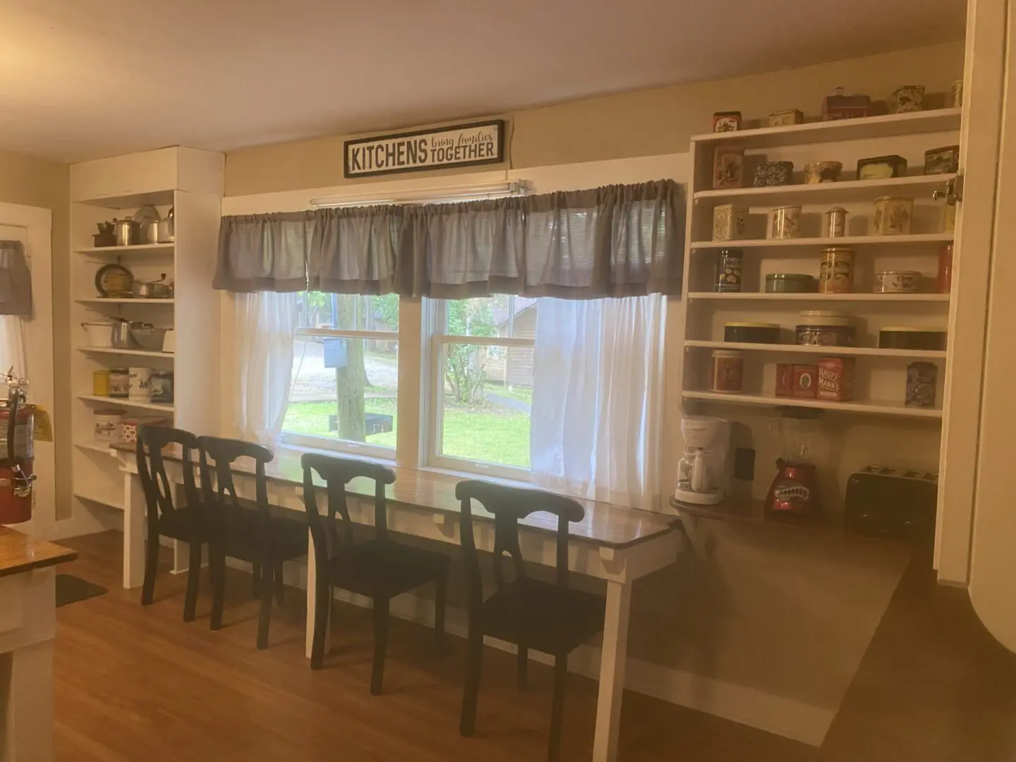 A dining room table with four chairs and two bookcases.
