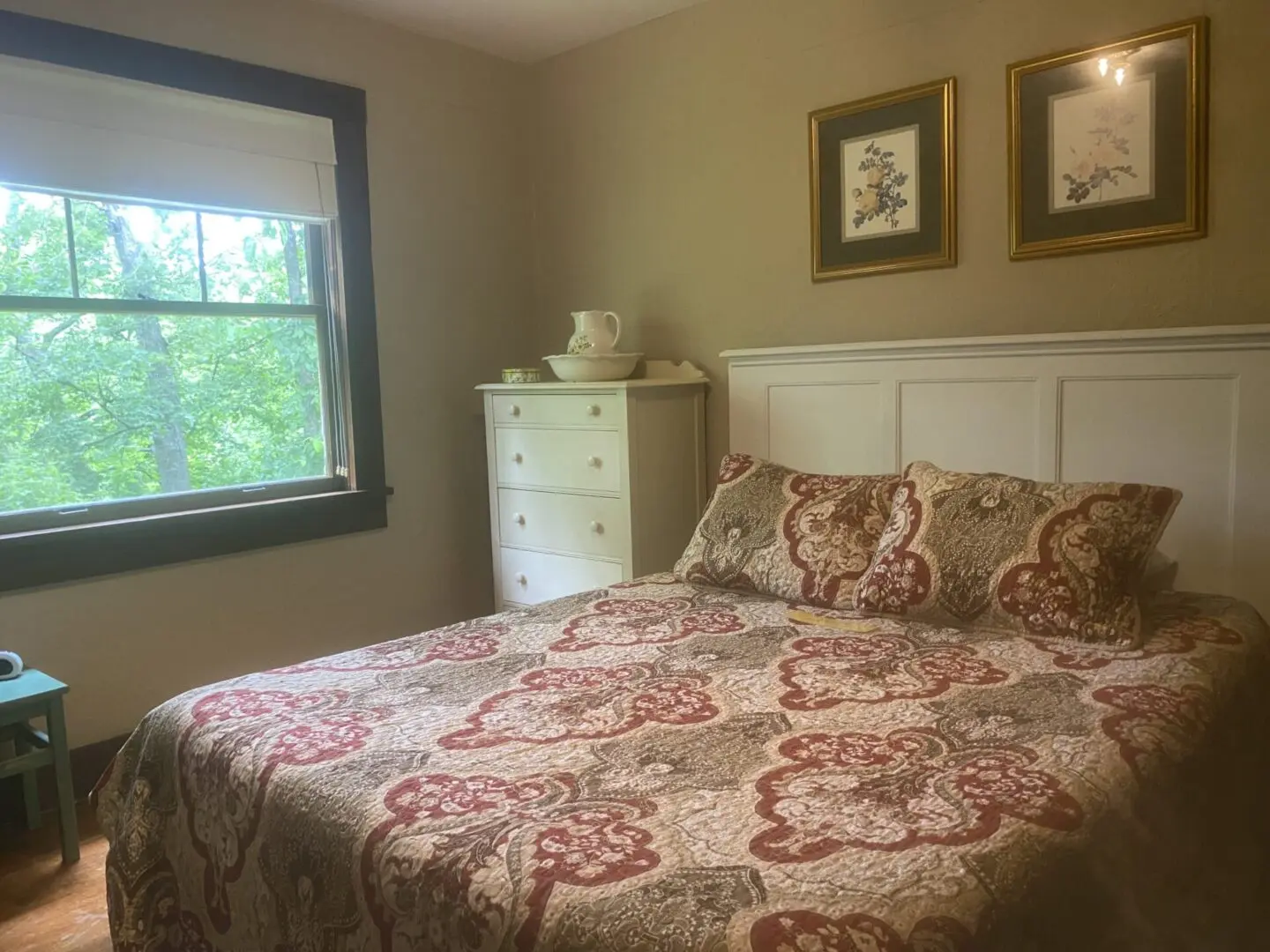 A bedroom with a bed, dresser and window.