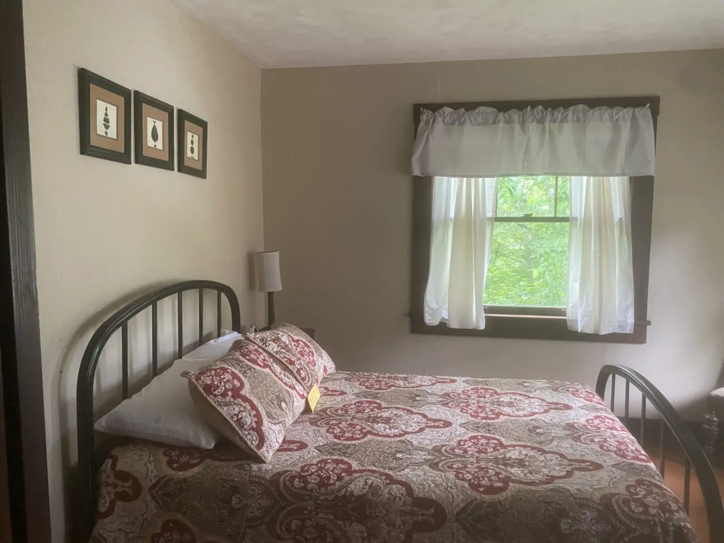 A bedroom with a bed, nightstand and window.