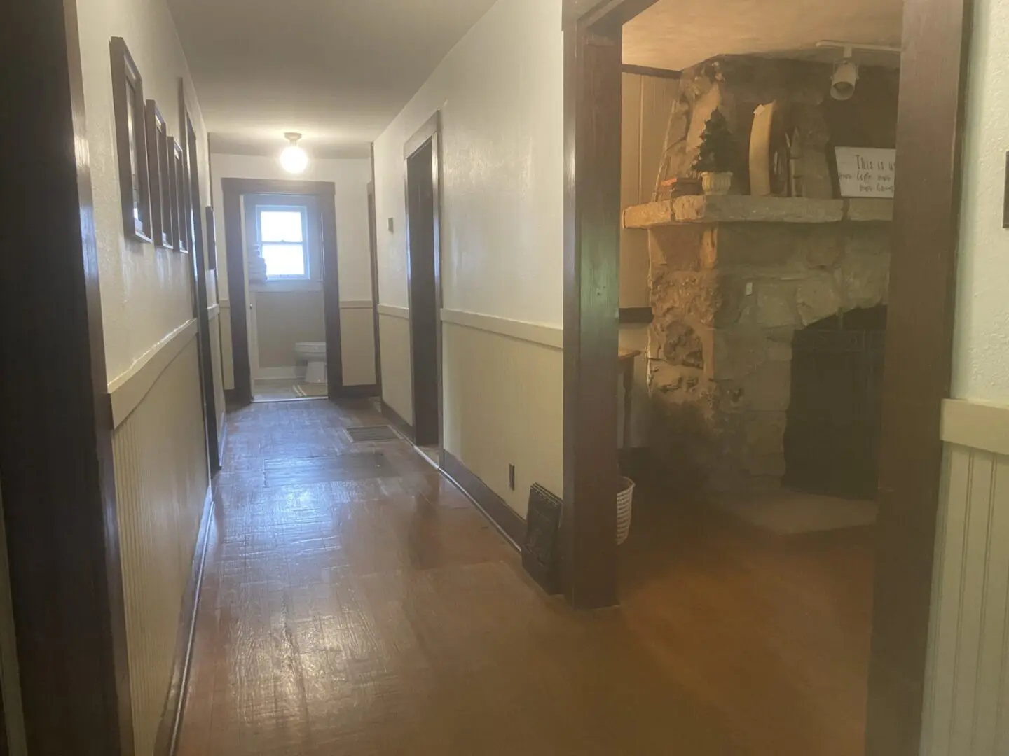 A hallway with wooden floors and white walls.