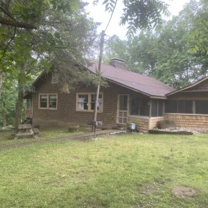 A house with a large yard and trees in the background.