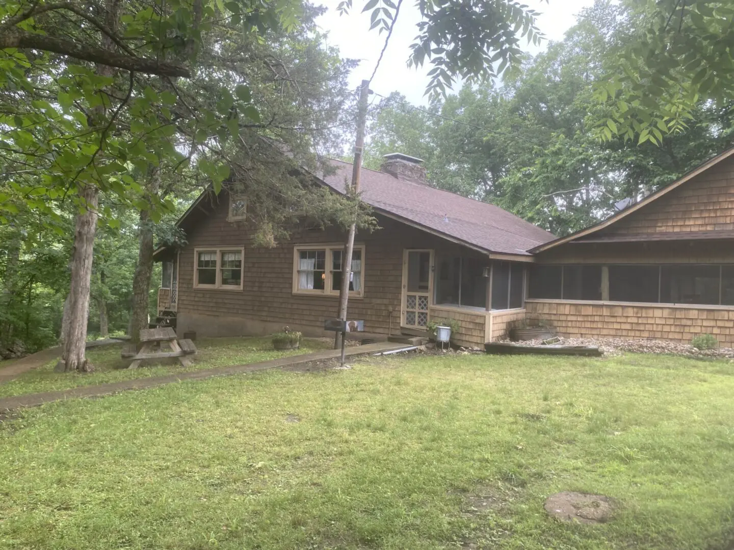 A house with a large yard and trees in the background.