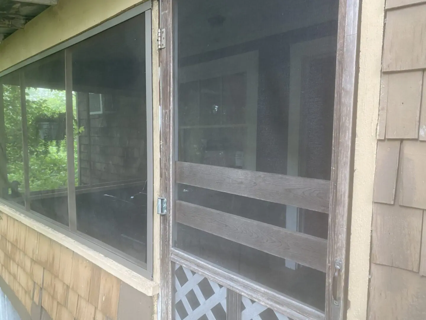 A screen door that is open on the outside of a house.