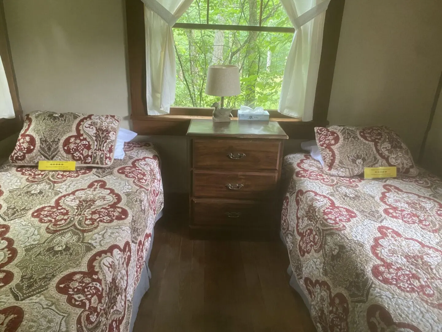 A bedroom with two beds and a dresser in the corner.