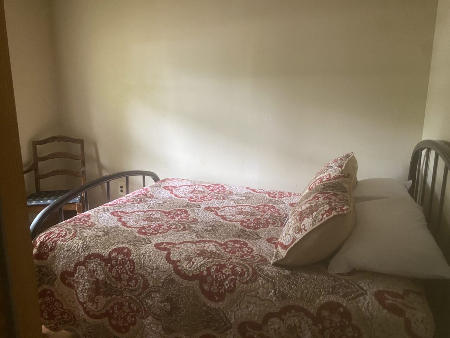 A bed with a red and white floral comforter.