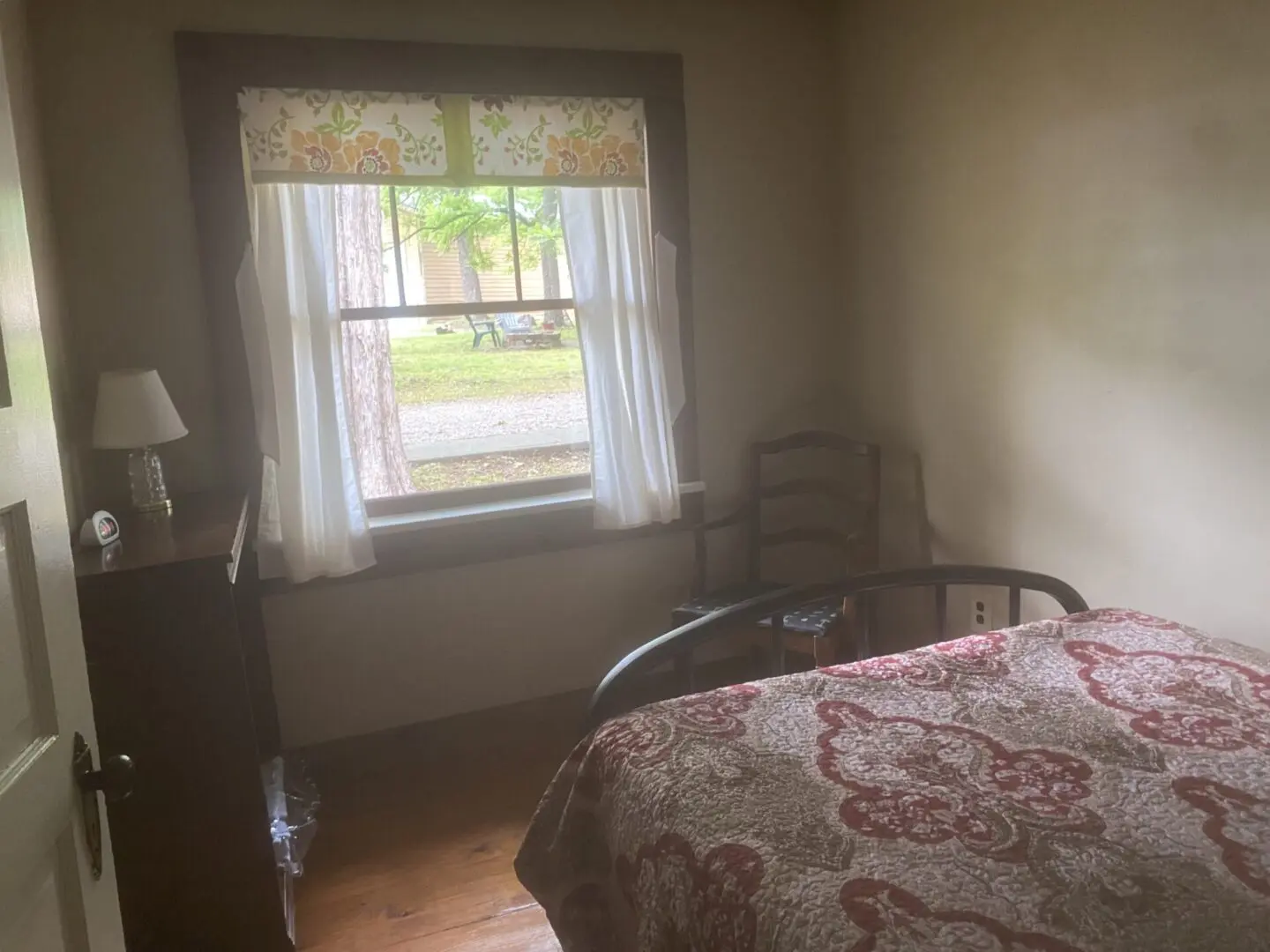 A bedroom with a bed, chair and window.