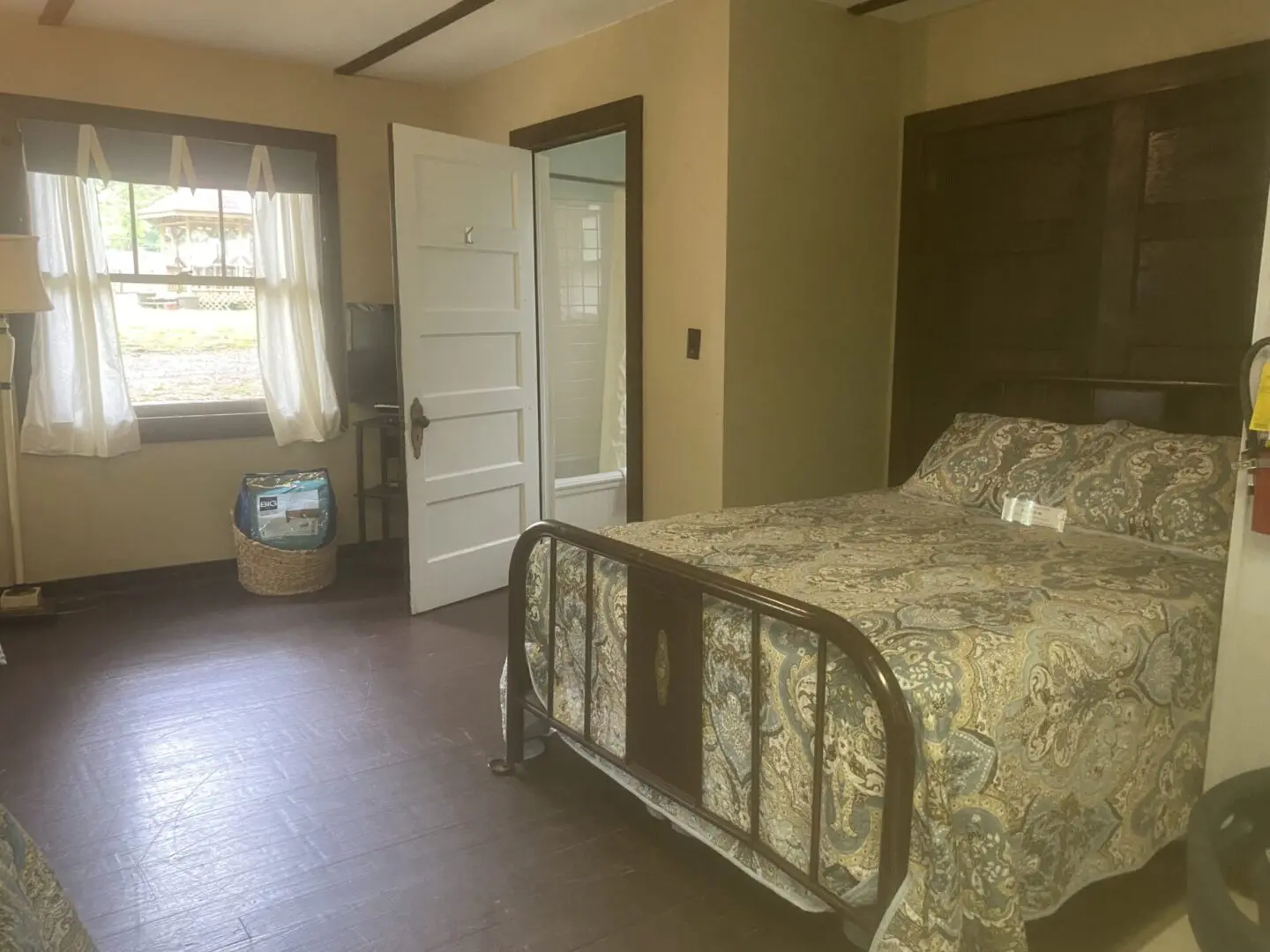 A bedroom with a bed, dresser and window.