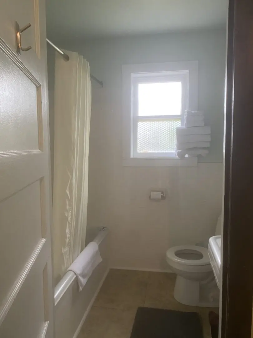 A bathroom with white walls and wooden floors.