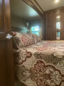 A bed with a brown and red floral comforter.