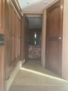 A hallway with wooden cabinets and a cat in it.
