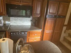 A kitchen with brown cabinets and black stove.