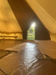 A tent with an open door and some sheets on the floor
