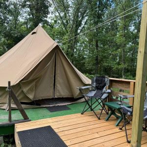 Tent and chairs on wooden deck outdoors.