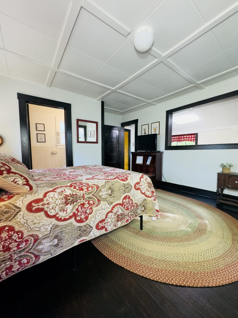 Bedroom with patterned bedspread and round rug.