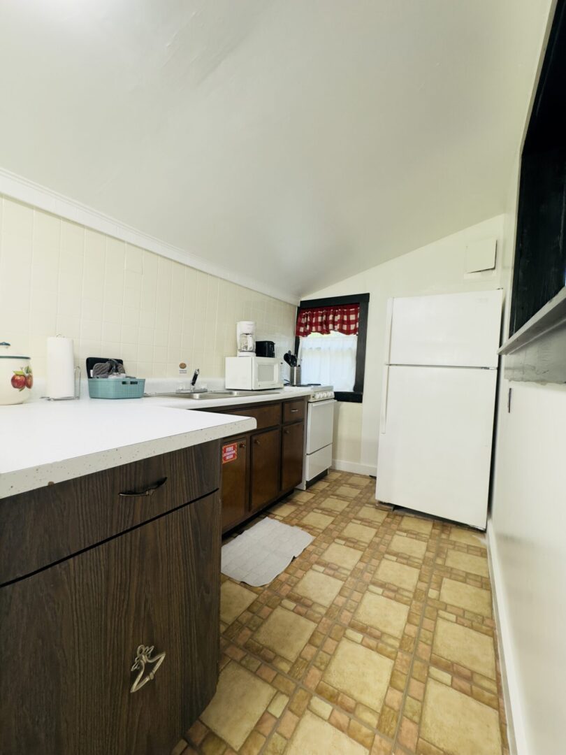 Compact kitchen with white fridge and cabinets.