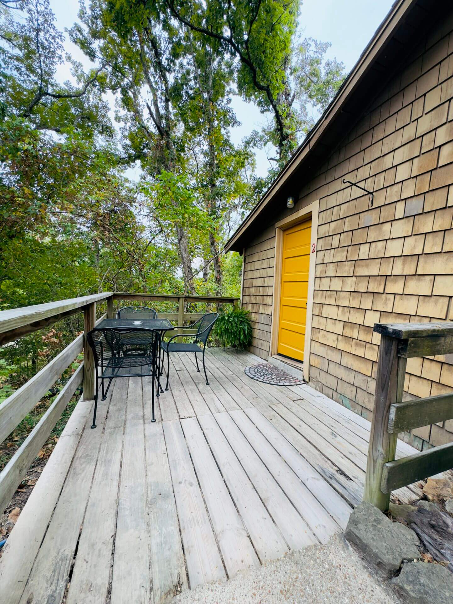 Wooden deck with chairs and yellow door.