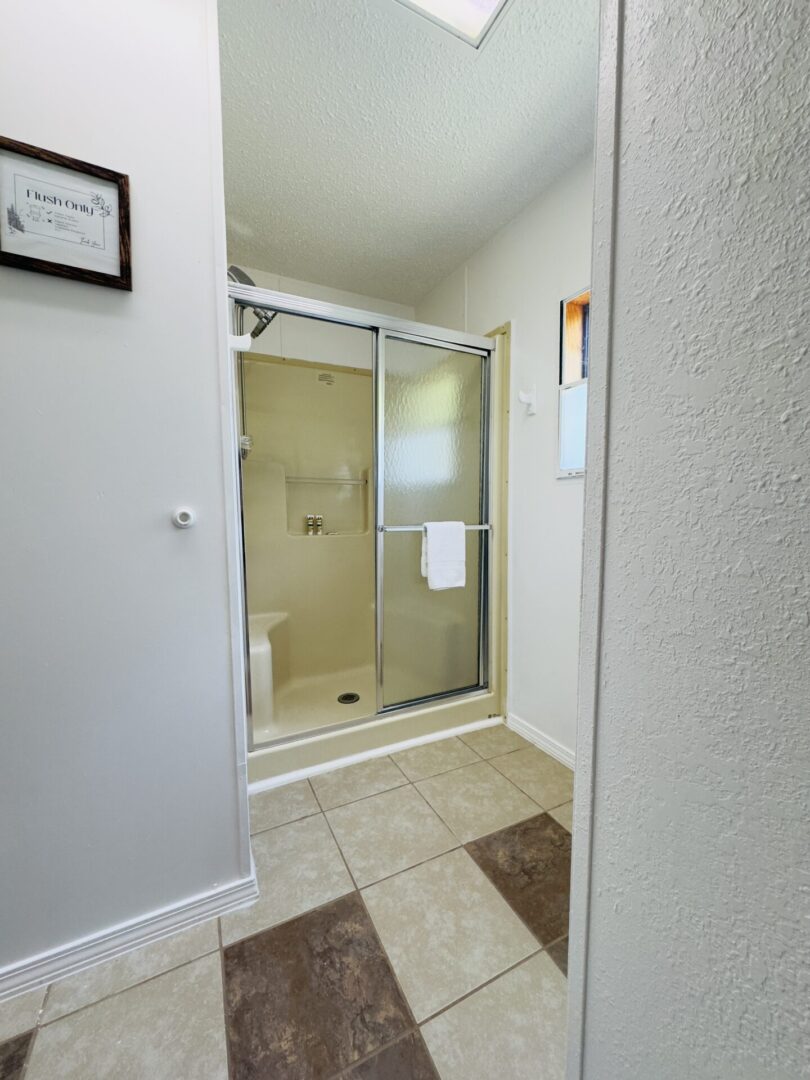 Bathroom with glass shower and tiled floor.