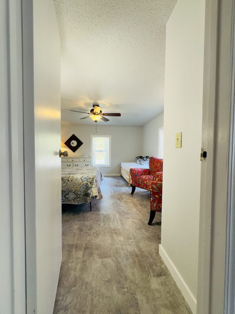 Bright bedroom with ceiling fan and chair.