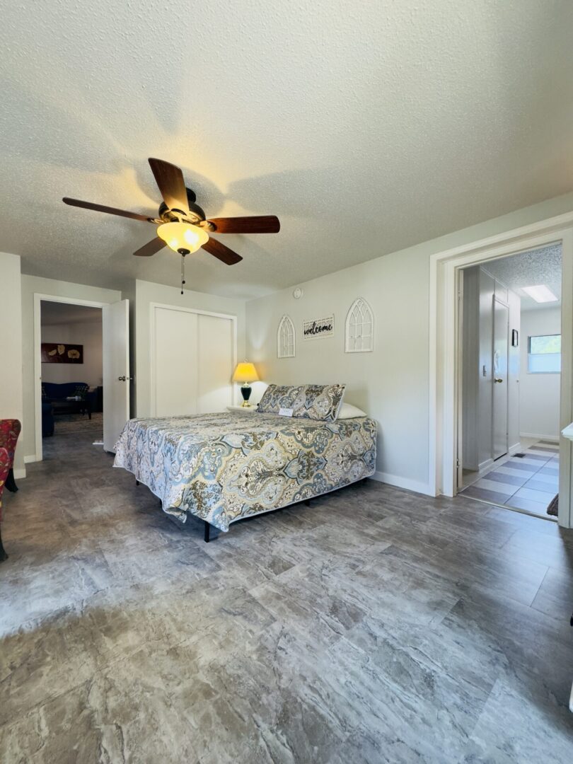 Bedroom with ceiling fan and patterned bedspread.
