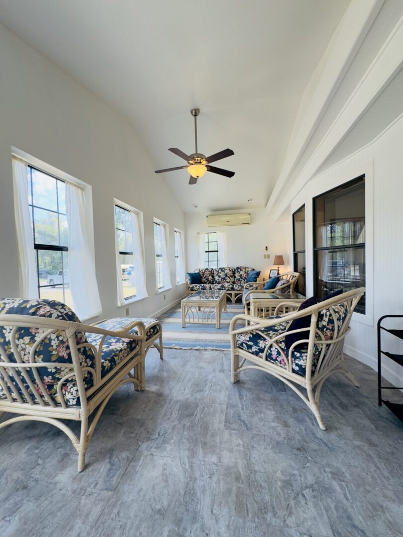 Bright sunroom with wicker furniture and fan.