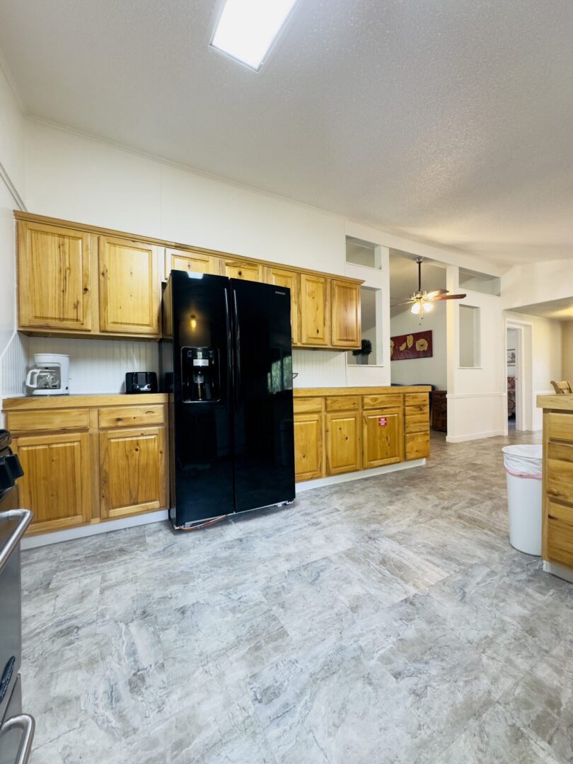 Spacious kitchen with wooden cabinets and fridge.